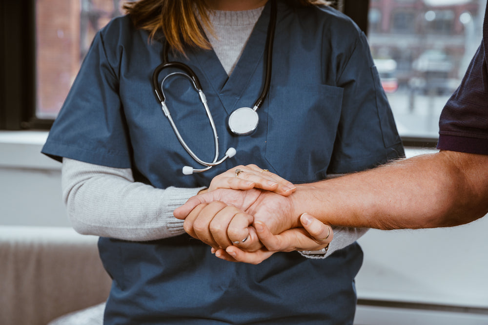 Médica de mãos dadas com paciente.